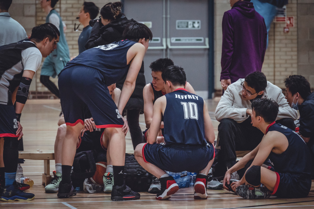 Players talking through a possession during a break in a gym