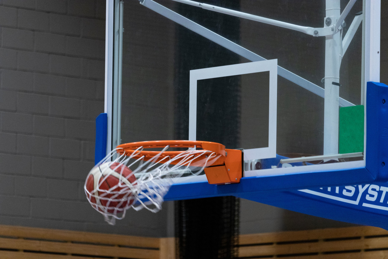 A basketball dropping through the net on an indoor court